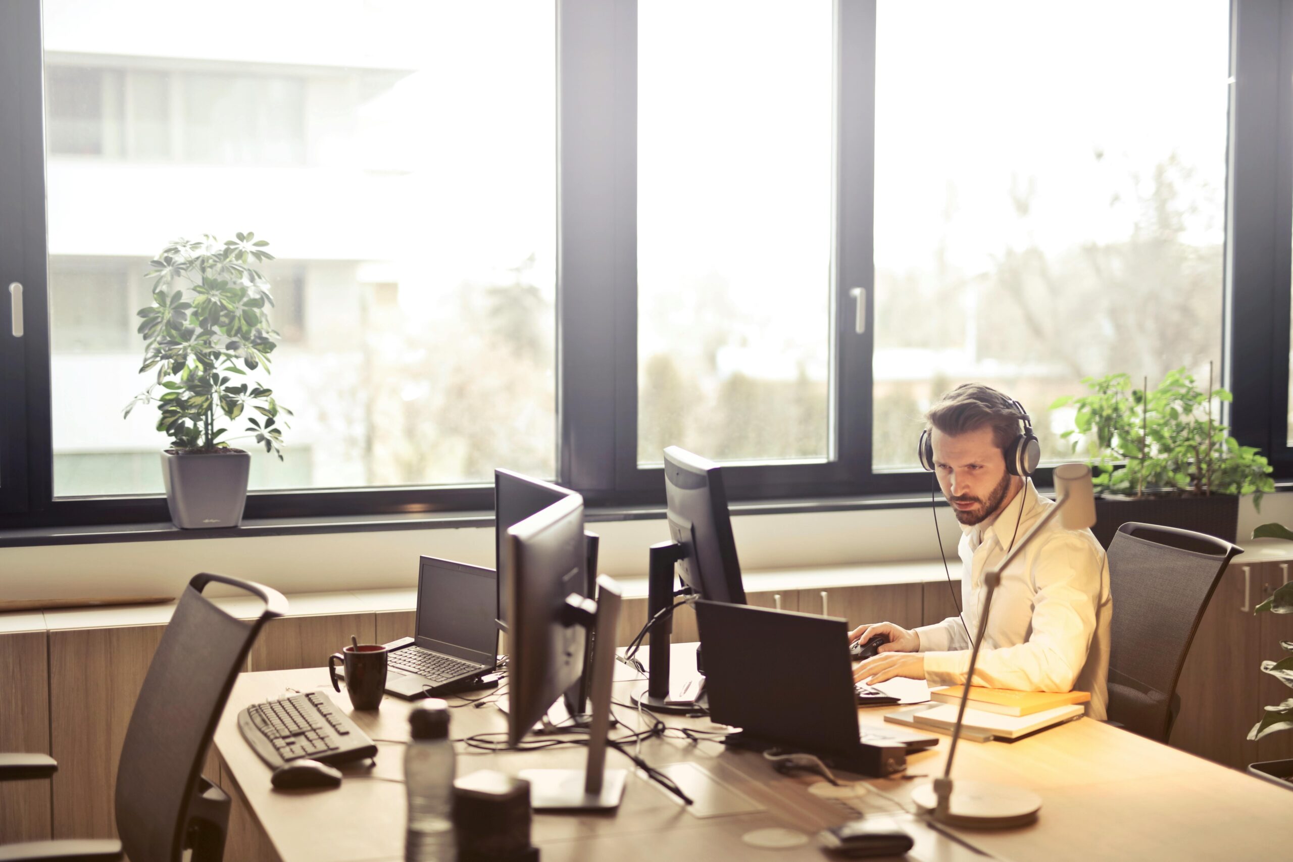 Man working with headphones on in an office by a large window